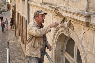 Artisan restaurateur en action sur façade ancienne à Sézanne
